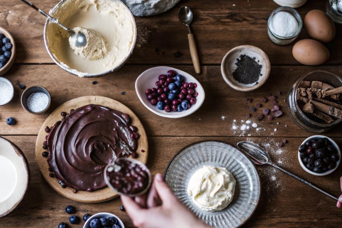 Flat-lay of Dark Chocolate Mousse Cake ingredients, including cocoa powder, dark chocolate, eggs, sugar, heavy cream, and espresso powder.