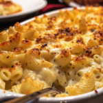 A creamy baked mac and cheese dish with a golden-brown, crispy topping, served in a white casserole dish.