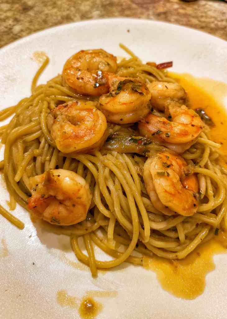 Shrimp and pasta recipes cooking in skillet with garlic and steam