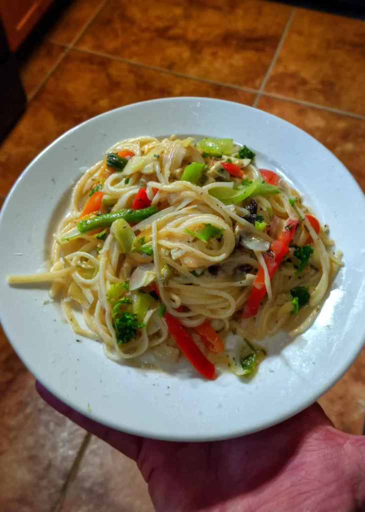 Fork lifting pasta primavera noodles with broccoli and zucchini