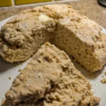 Fresh Irish Soda Bread loaf with cross cut on top on wooden table