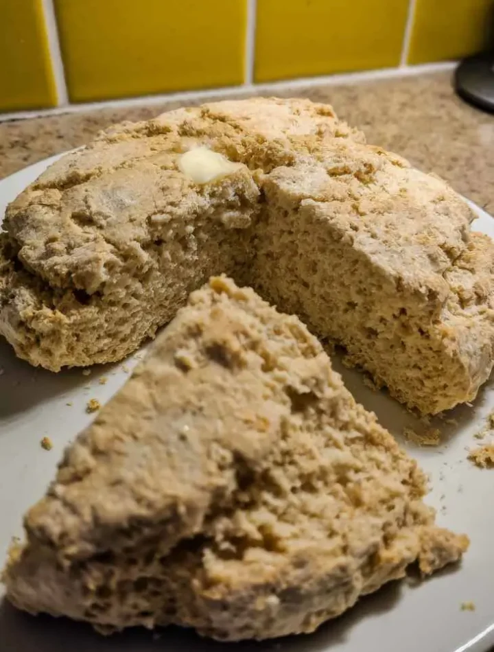 Fresh Irish Soda Bread loaf with cross cut on top on wooden table