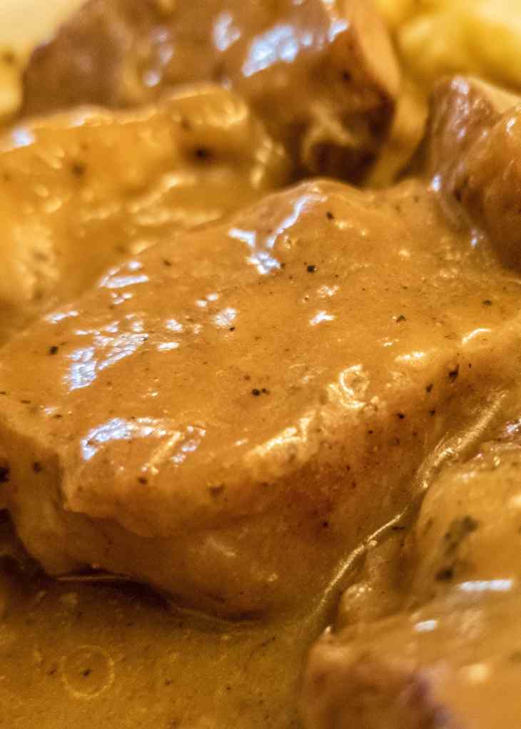 Raw pork chops in the crock pot with onions and sauce before cooking