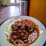 Bowl of red beans and rice with sausage on wooden table