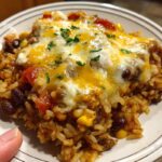 Brown rice and black bean casserole in a glass baking dish with melted cheese