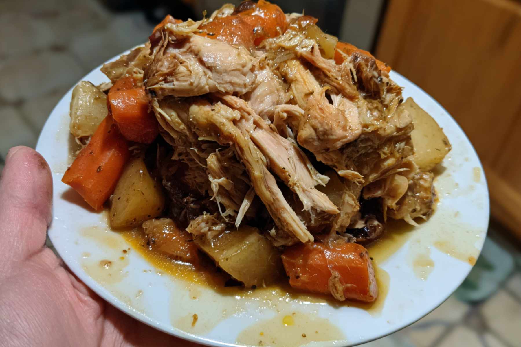 Chicken cooks in barbecue sauce inside a slow cooker for a chicken recipes crockpot variation. The sauce coats the meat thickly.