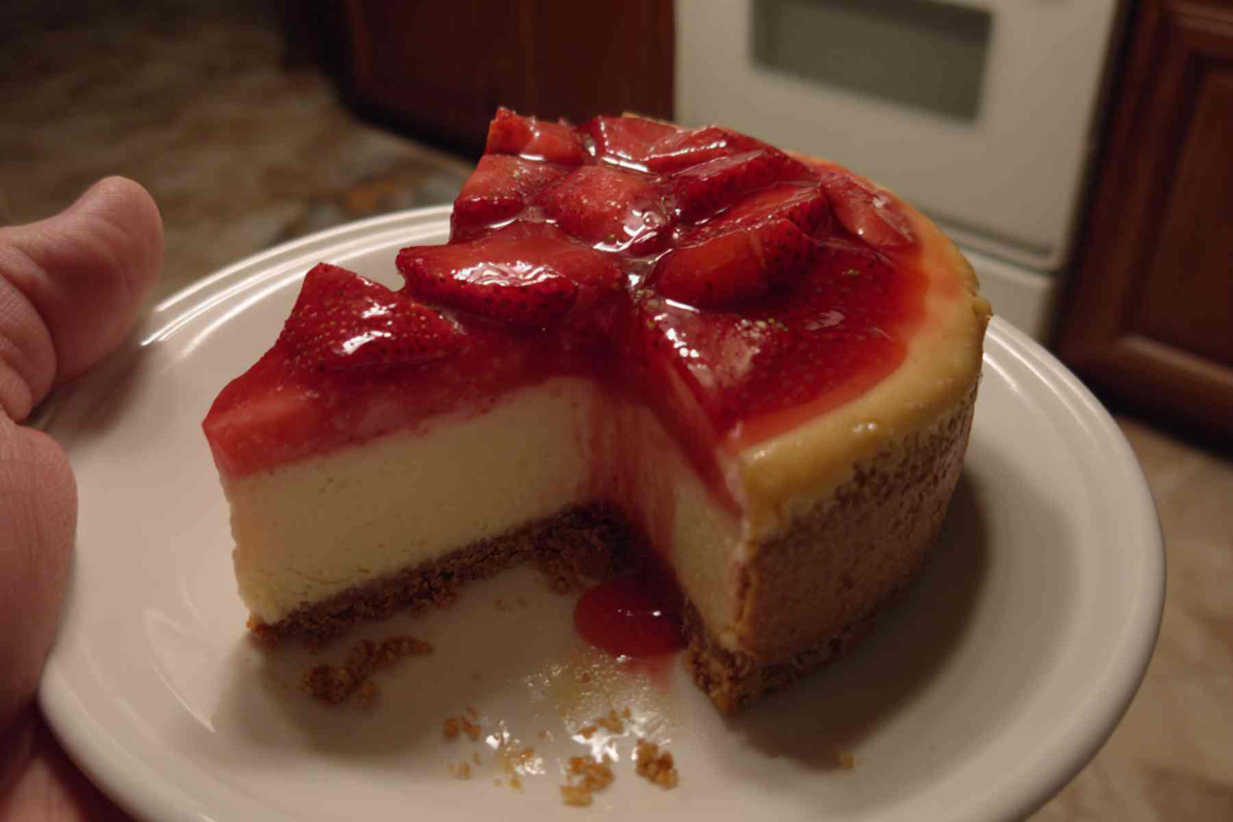Fork cutting into strawberry cheesecake slice showing creamy texture